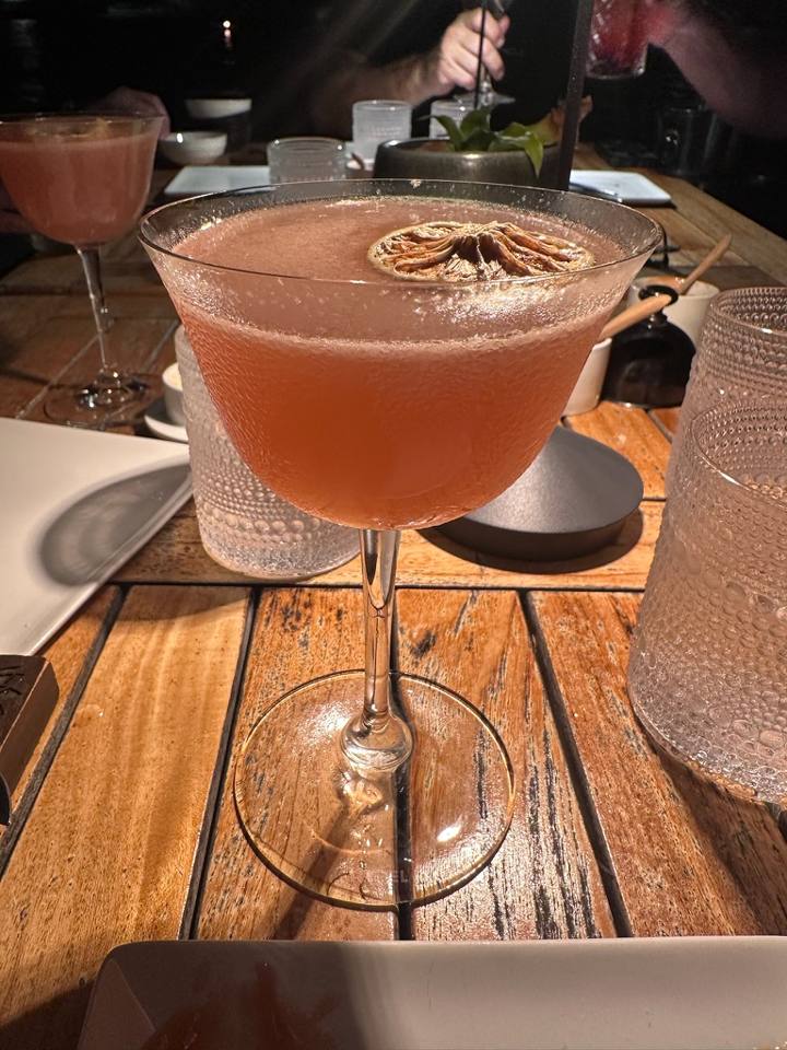 A pink cocktail on a wooden table at Baoase