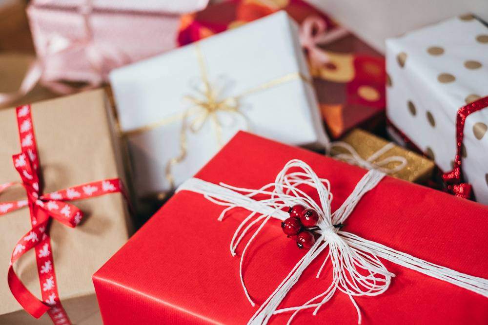 A pile of wrapped holiday gifts in red, kraft and gold polka dot paper