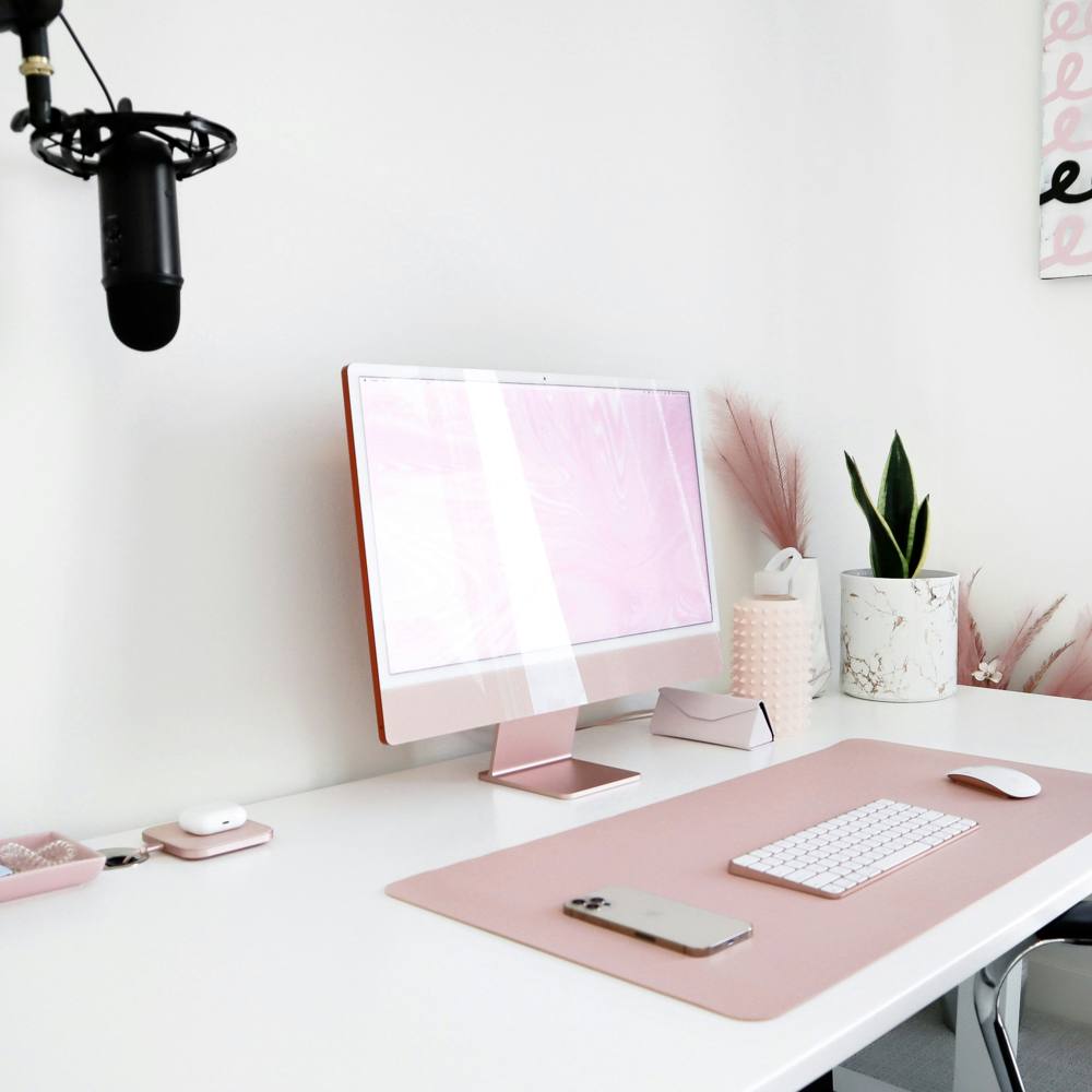 A pink desk setup with a pink computer and pampas grass