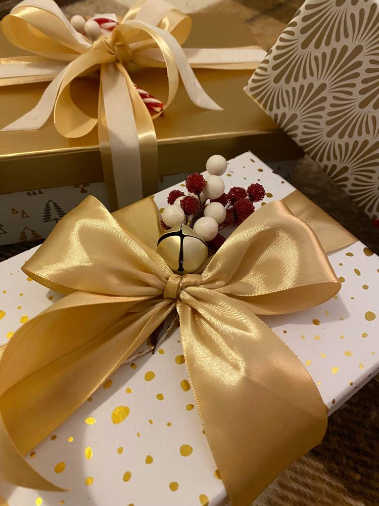 Gifts wrapped in gold and white paper with gold satin bows