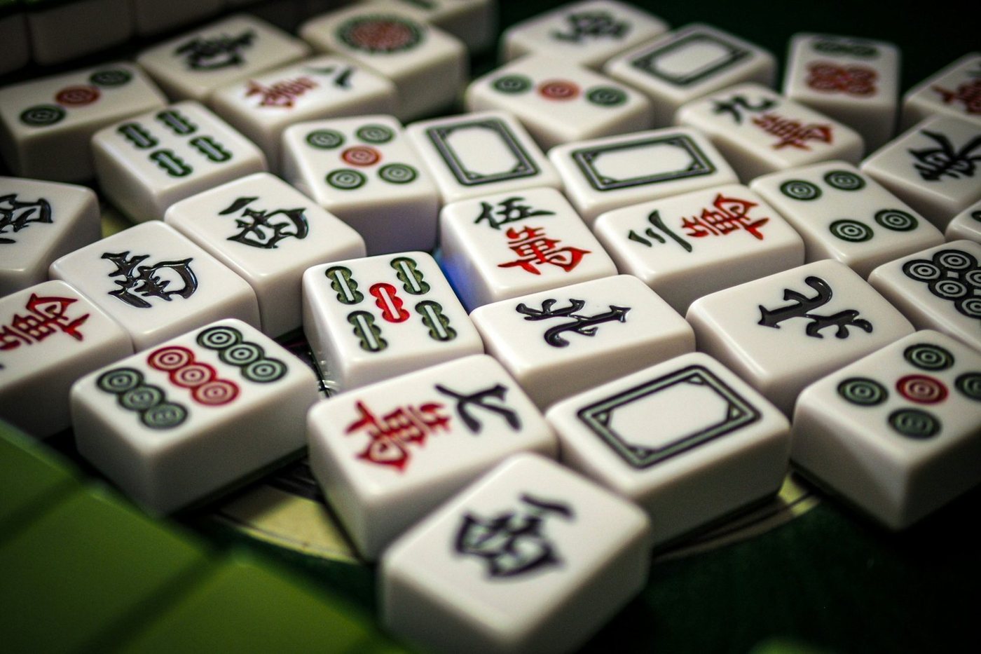 Close-up of traditional mahjong tiles scattered on a green table